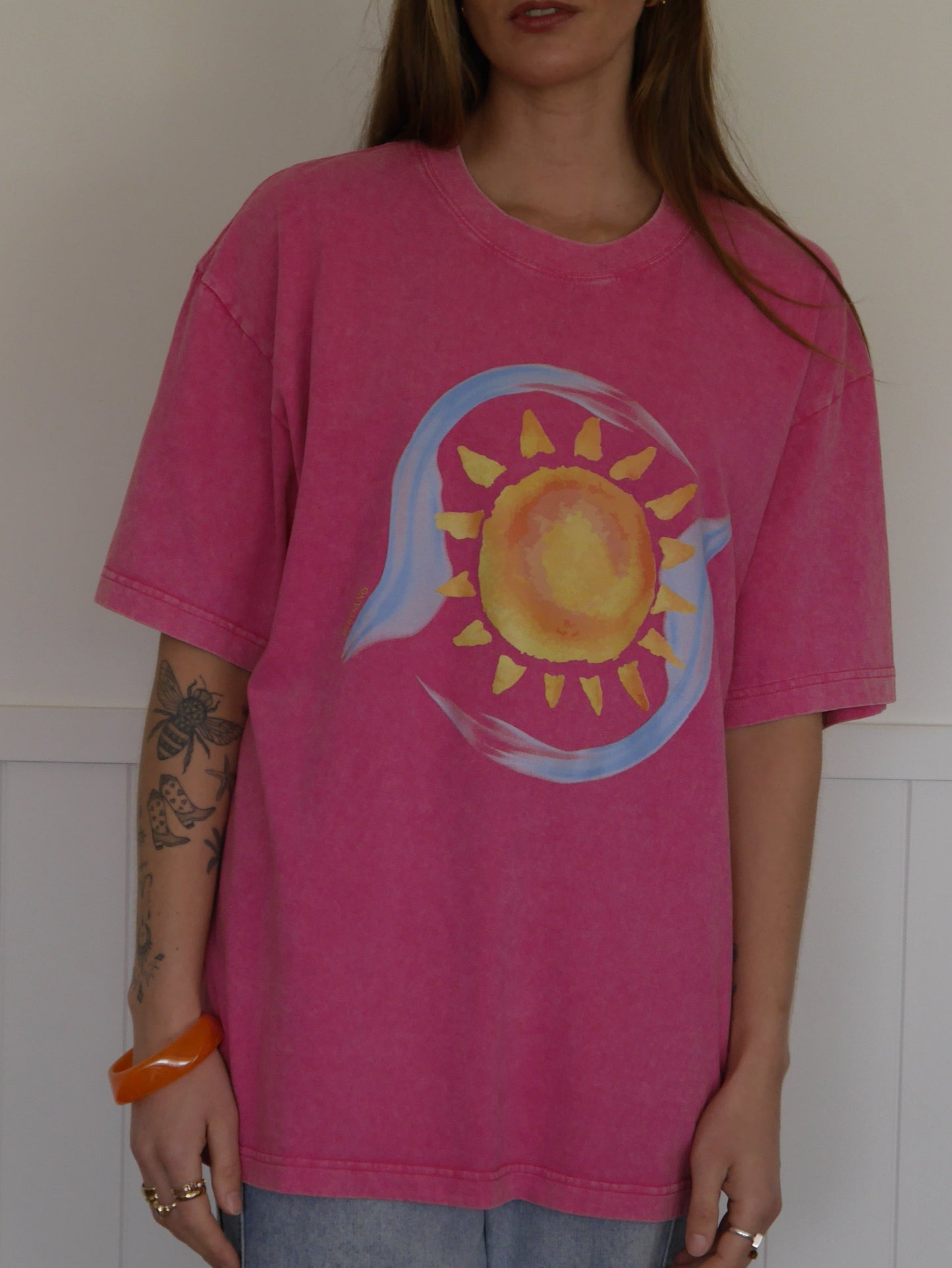 Person wearing a pink t-shirt with a sun design on a white background